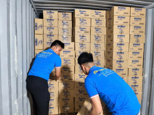 People arranging cartons inside a container